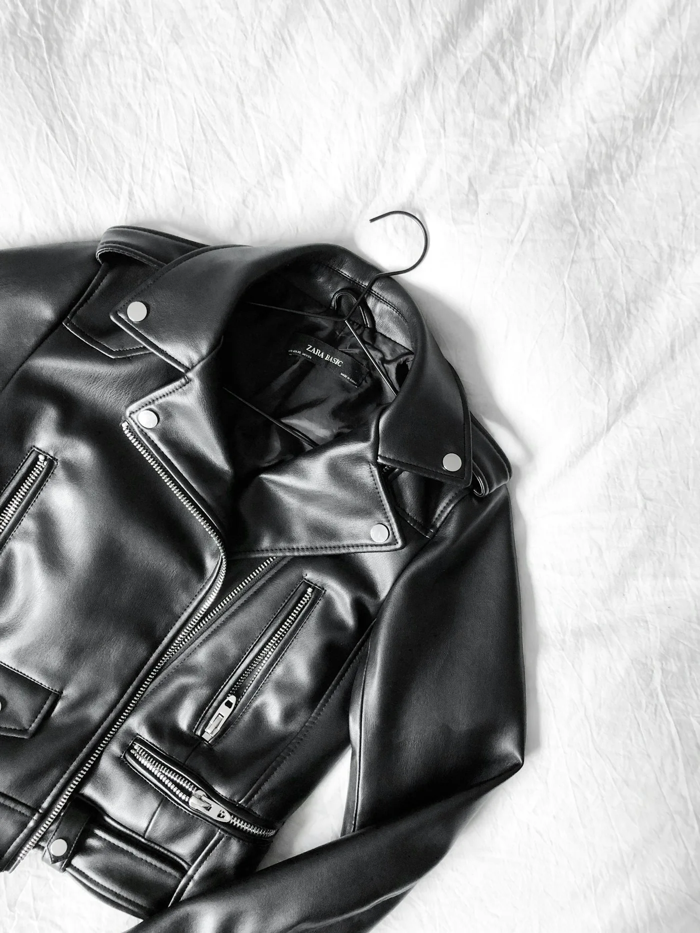 Black leather jacket laid on a pale surface