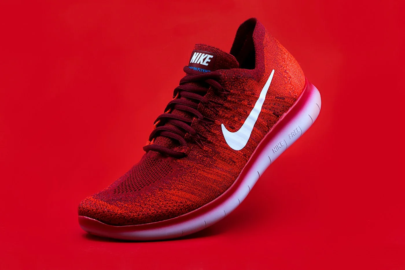 Red athletic shoe photographed against a red background