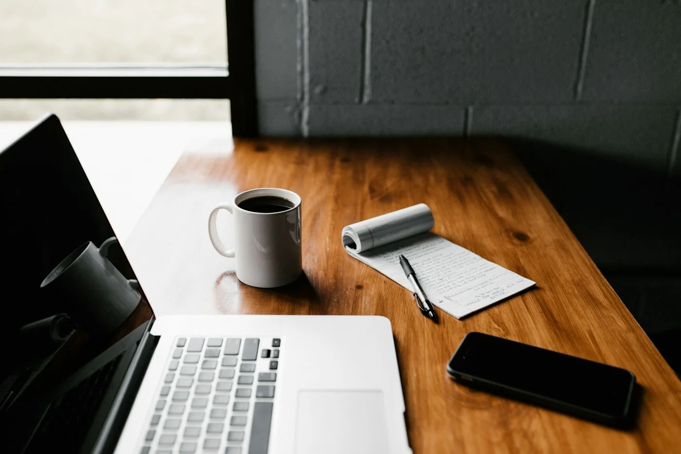 Laptop, smartphone, notebook and coffee on a wooden desk